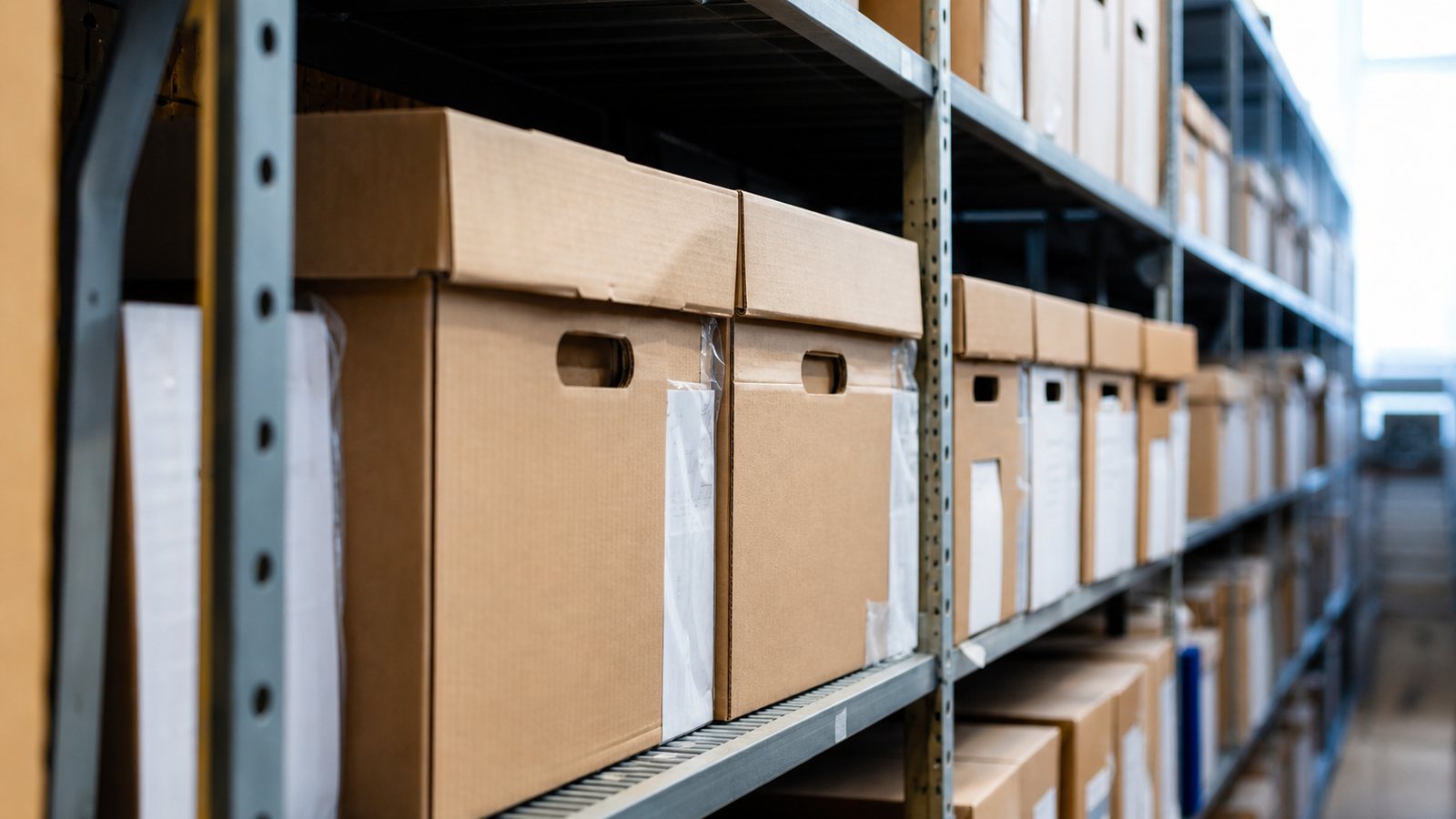 Anciens registres et boîtes d'archives rangés sur les étagères d'une réserve de brocante